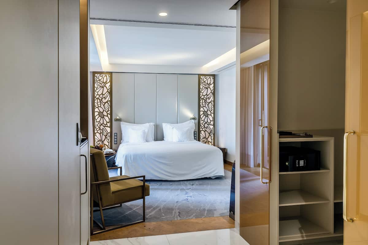 A modern bedroom with a large bed, a desk, and a wardrobe.