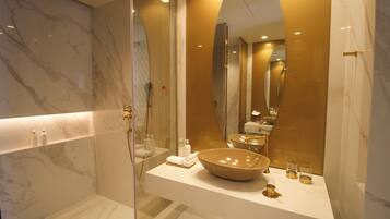 Un baño moderno con un espejo grande, tocador de mármol y cabina de ducha con paredes de vidrio.