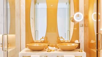 A modern bathroom with two sinks, a large mirror, and a vanity with towels.