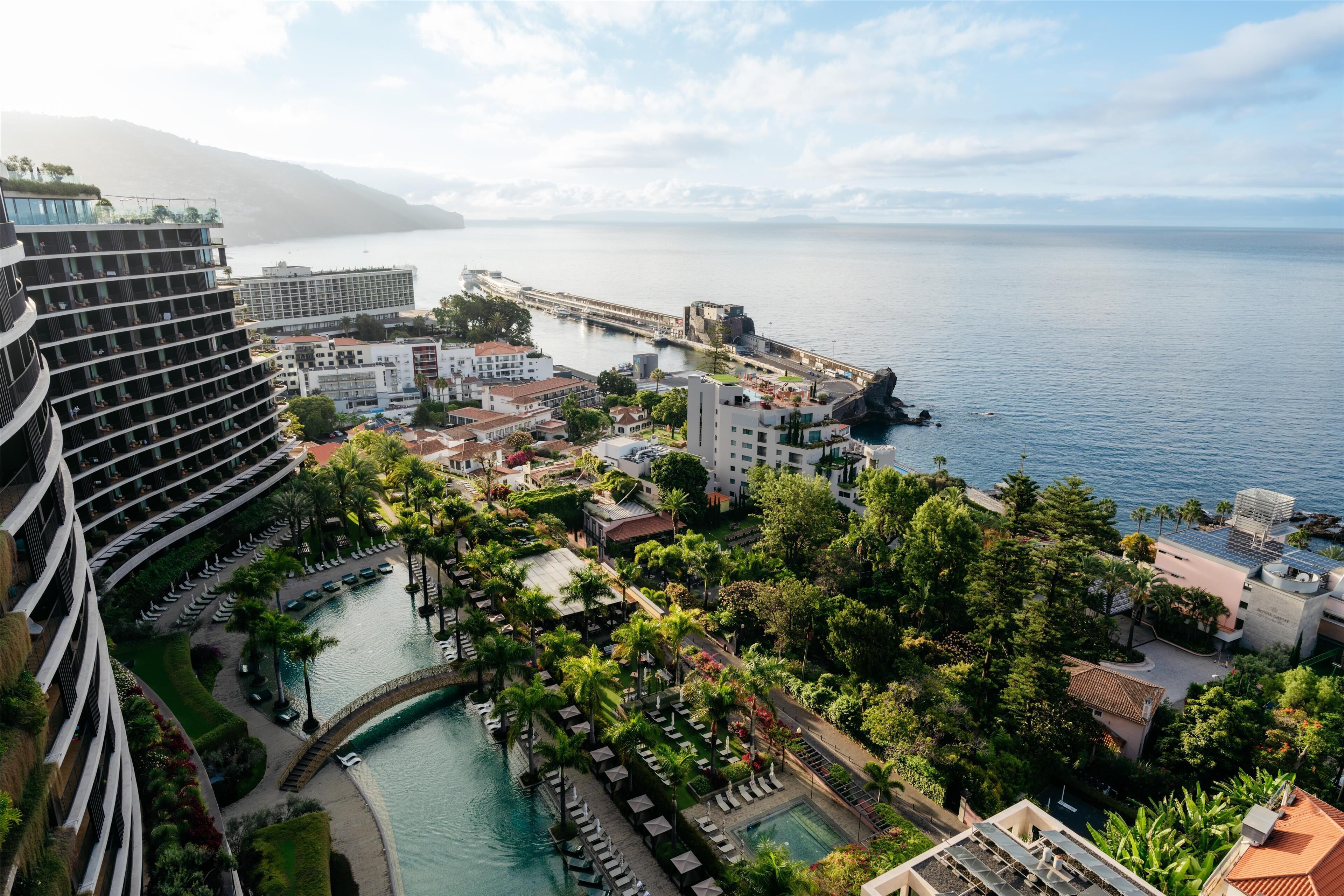 A coastal hotel with multiple buildings, a marina, and a large body of water.