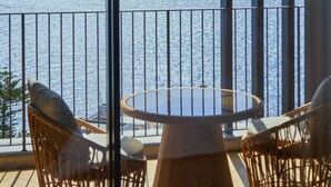 A balcony with wicker chairs and a table, overlooking a body of water. - Savoy Palace - The Leading Hotels of the World - Savoy Signature (Funchal)
