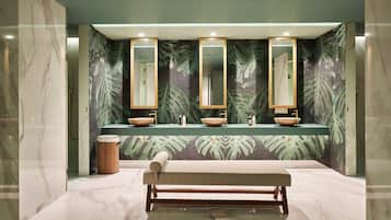 A modern bathroom with three sinks, large mirrors, and a bench.