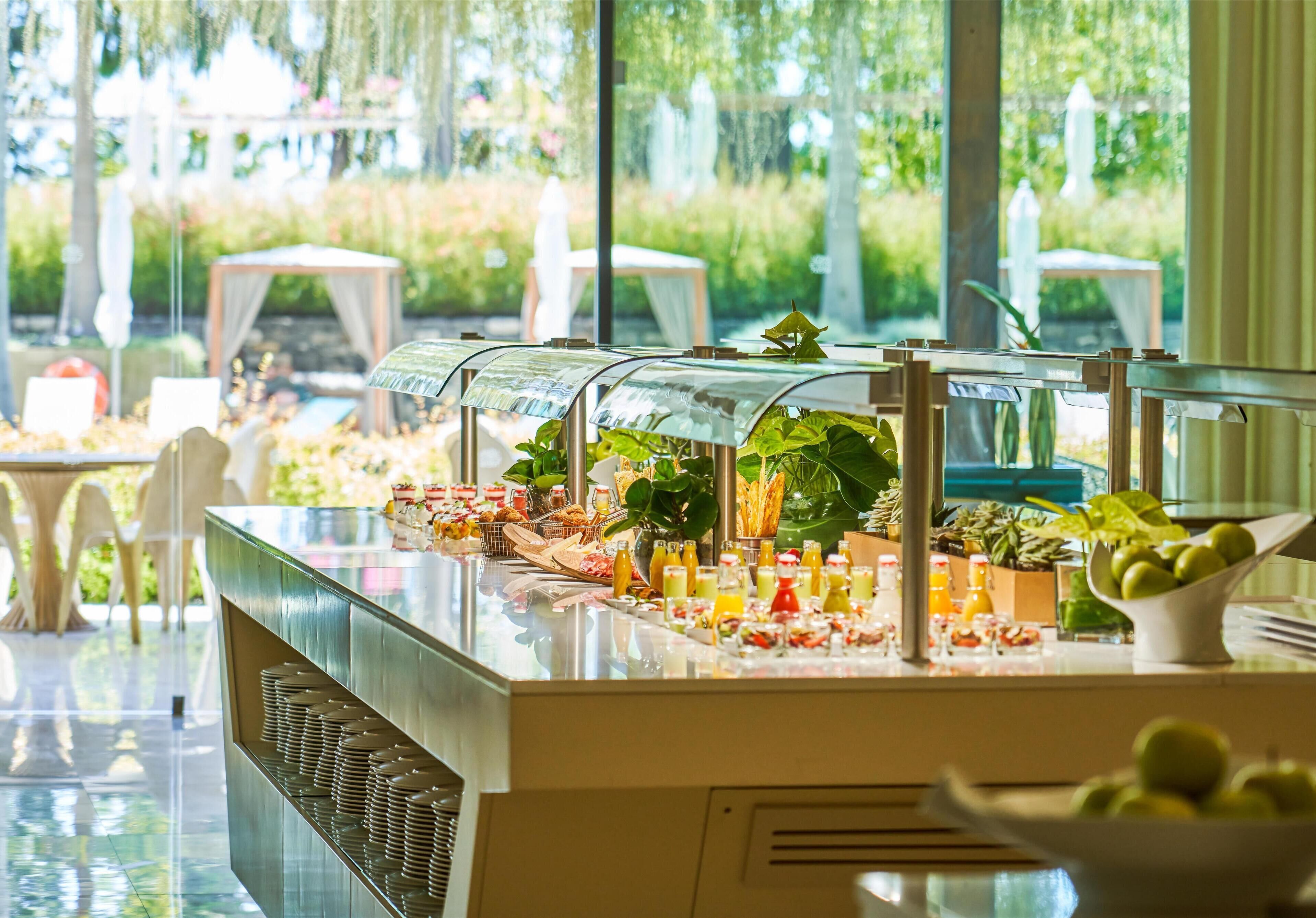 A buffet with various food items and drinks, surrounded by tables and chairs.