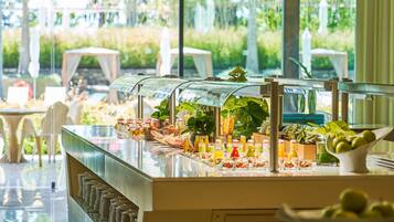 A buffet with various food items and drinks, surrounded by tables and chairs.