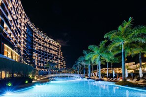A nighttime view of a hotel with a swimming pool, palm trees, and a bridge. - Savoy Palace - The Leading Hotels of the World - Savoy Signature (Funchal)