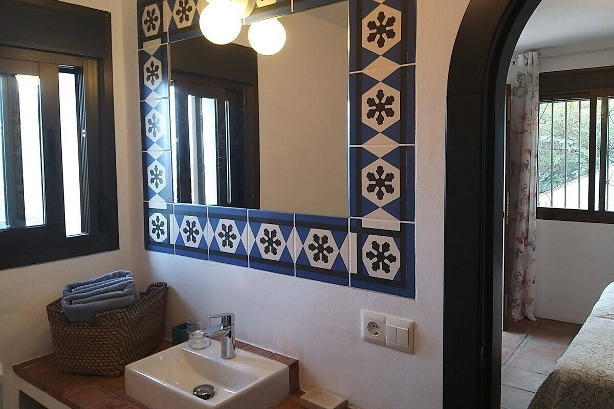 A bathroom with a sink, mirror, and decorative tiles.
