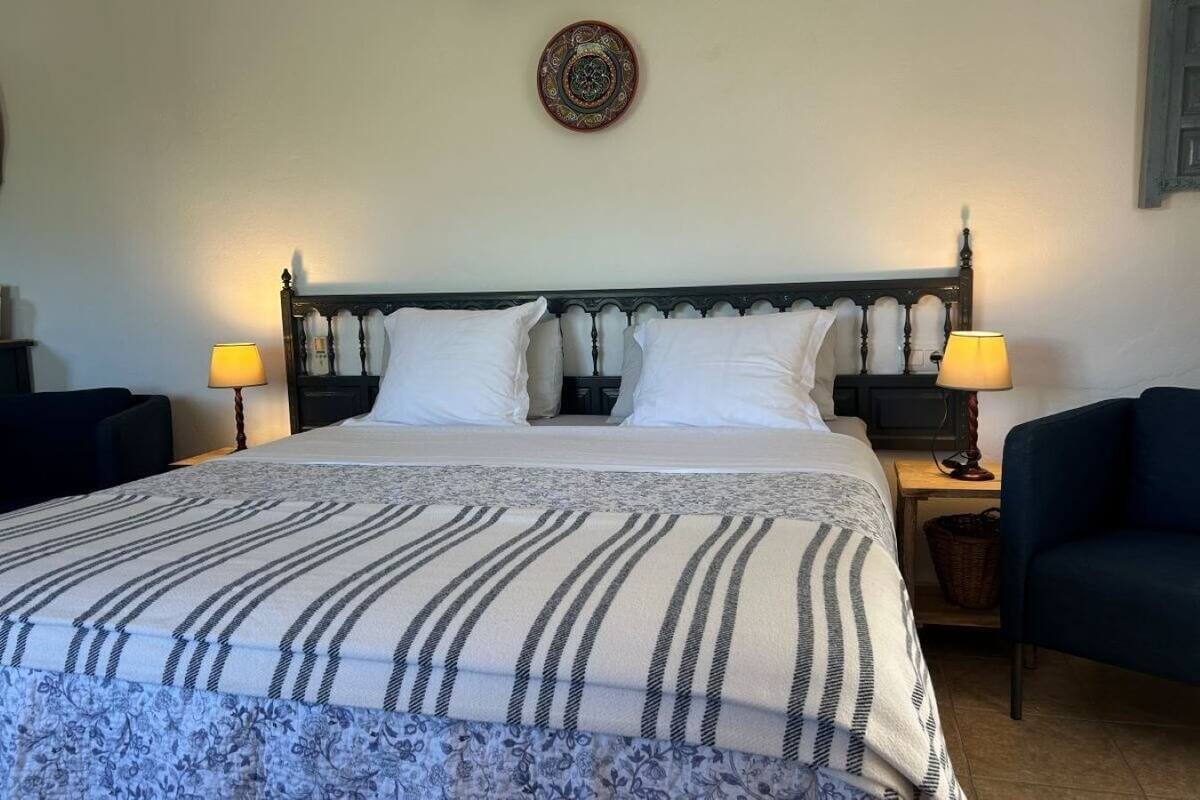A neatly made bed with striped bedding, two bedside lamps, and a decorative wall piece.