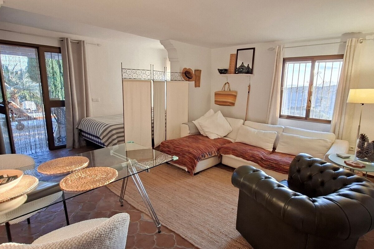 Un salon comprenant une table basse en verre, un canapé, un fauteuil en cuir et un coin repas avec une table et des chaises.