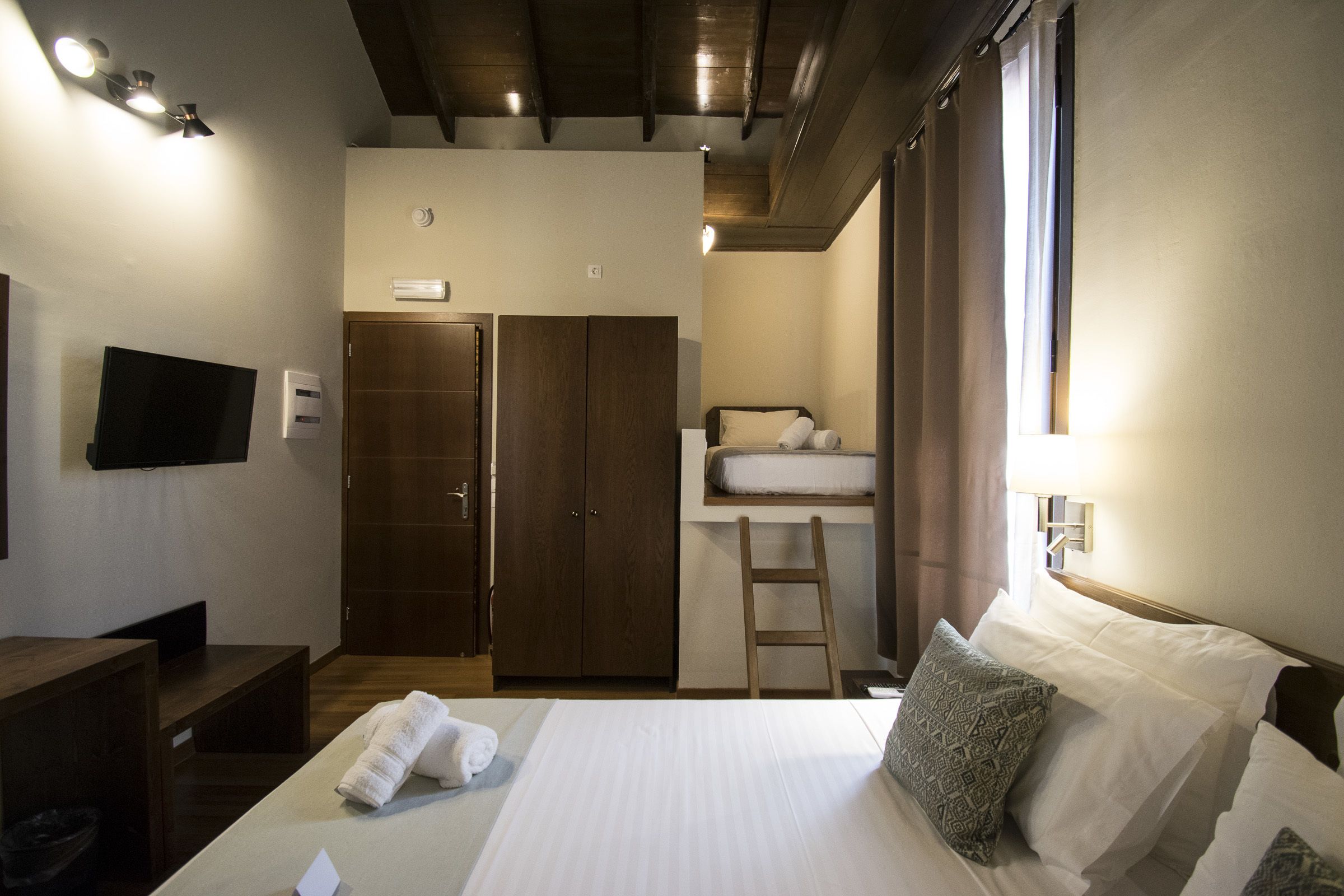 Habitació d'hotel amb llit, escriptori, televisió, armari i bany.