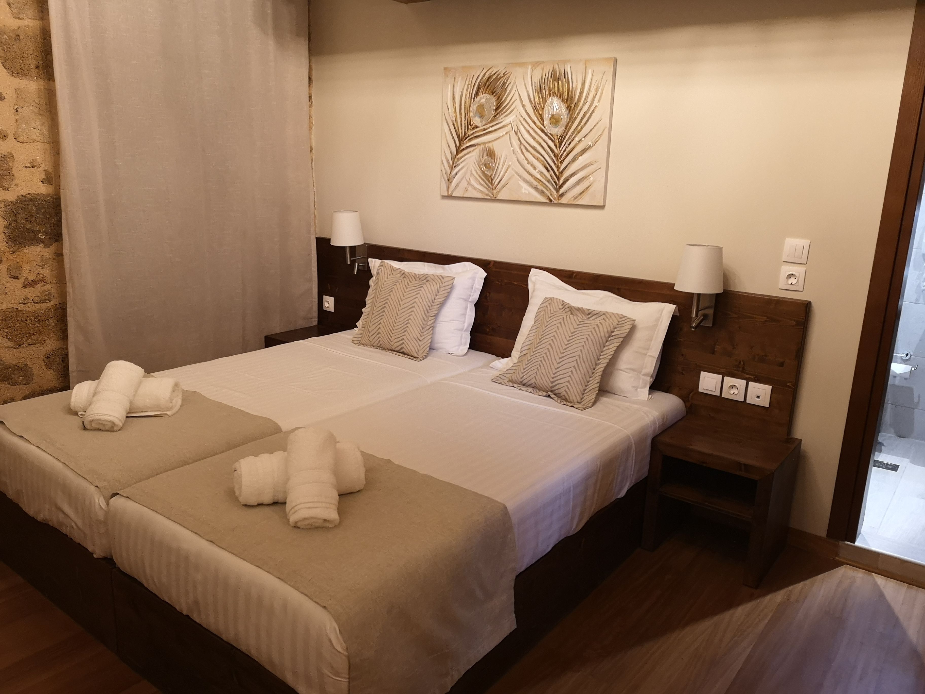 A double bed with two pillows, a nightstand, a wall-mounted lamp, and a decorative piece above the bed.