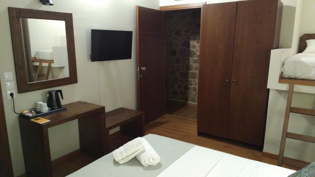 A hotel room with a bed, a desk with a coffee maker, a mirror, a wardrobe, and a television.