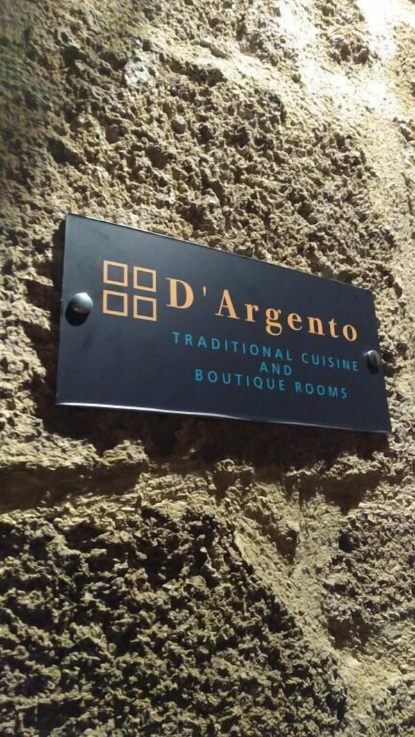 A sign for 'D'Argento' with text indicating it offers traditional cuisine and boutique rooms.