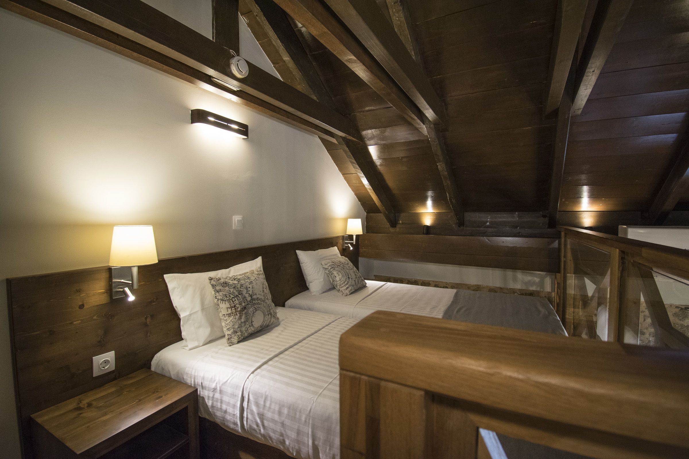 A room with two beds, wooden headboards, and bedside lamps.