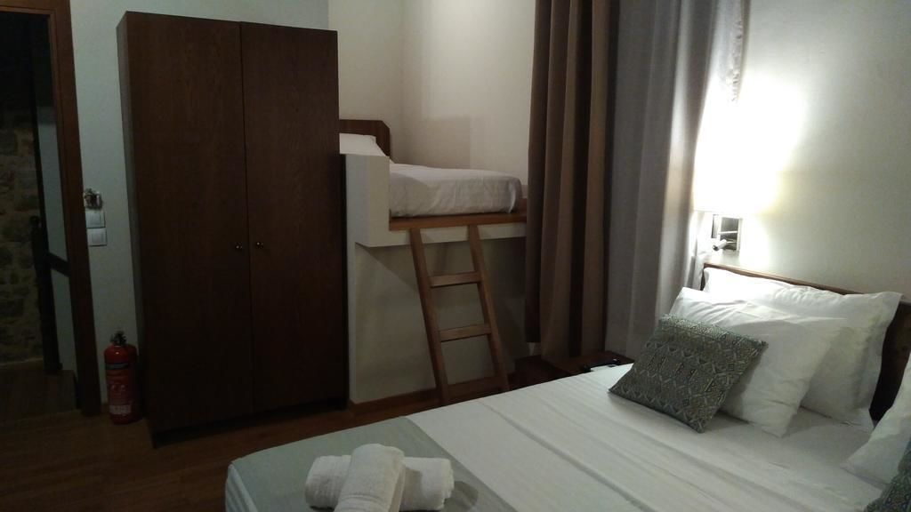 A bedroom with a bunk bed, a wardrobe, a ladder, a bed with pillows, and a fire extinguisher.