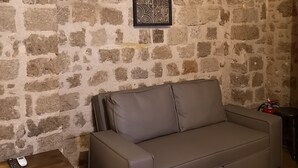 Een kamer met stenen muren, een bank en een kleine tafel.