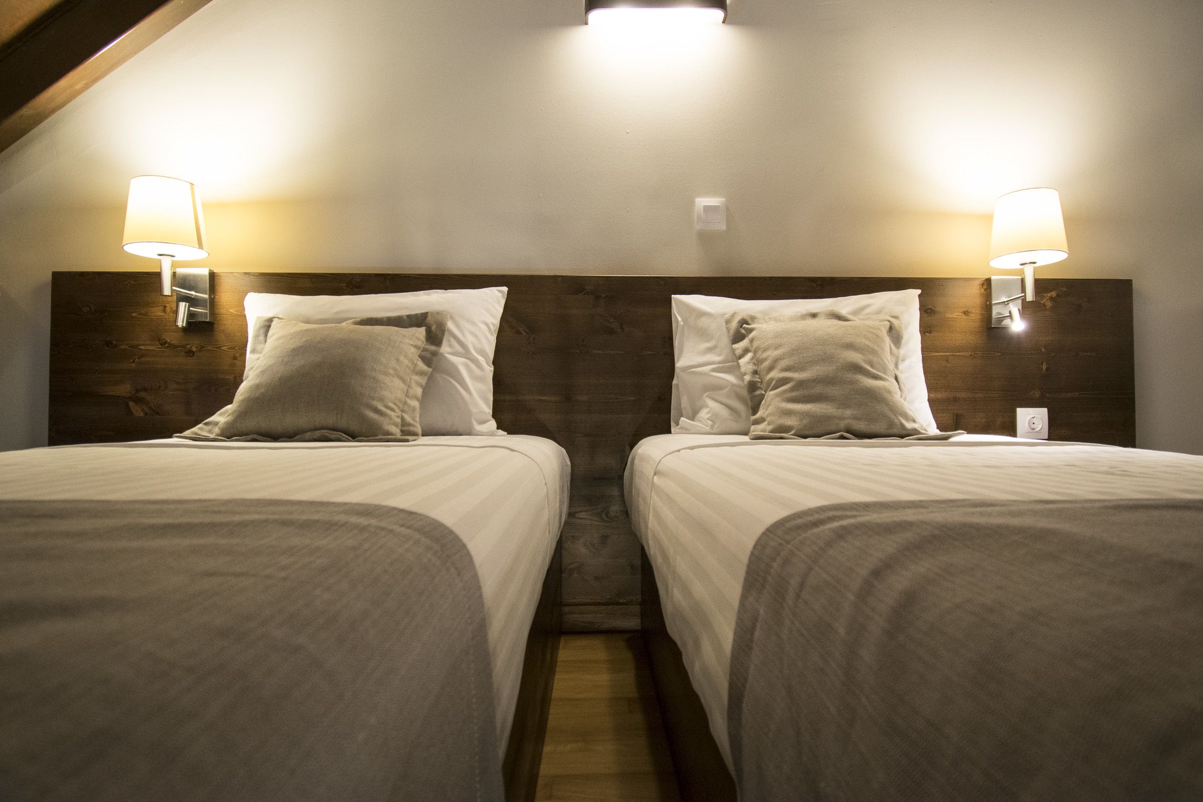 A twin room with two beds, each with a headboard, and bedside lamps.