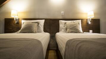 A twin room with two beds, each with a headboard, and bedside lamps.