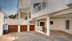 Un edificio residencial de varios niveles con un patio empedrado, puertas de garaje de madera y balcones con barandillas.