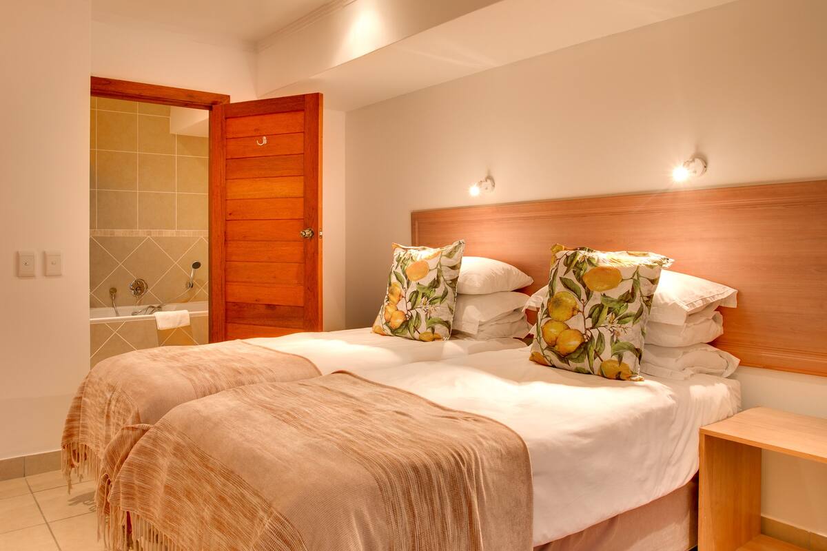 A double bed with floral pillows, a wooden headboard, and a nightstand.