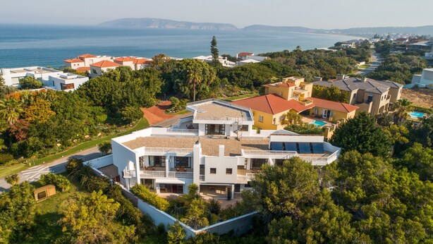 Una casa moderna con un balcón grande, piscina y vista al mar.