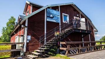 Un bâtiment en bois avec un escalier menant à un balcon, une enseigne indiquant « FISKMUSEUM », et une petite fenêtre.