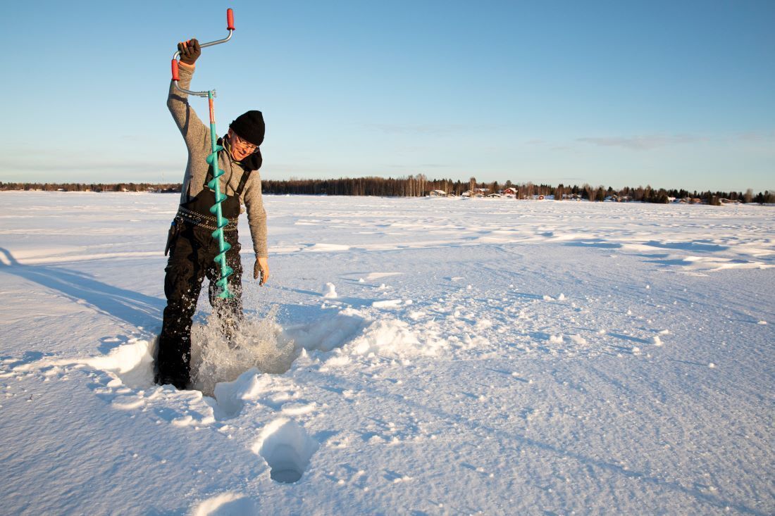 A person in a snowy outdoor setting, holding a tool that appears to be used for breaking ice or snow.