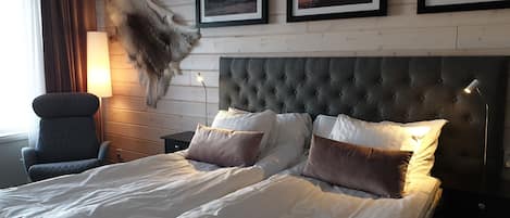 Una habitación de hotel con una cama grande, una silla, una mesita de noche y una lámpara fijada a la pared.