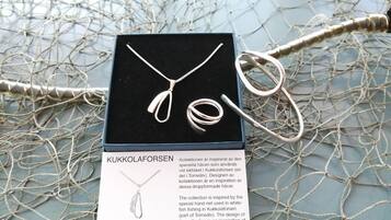 Una caja de joyería con un collar y aretes, sobre un fondo de red.