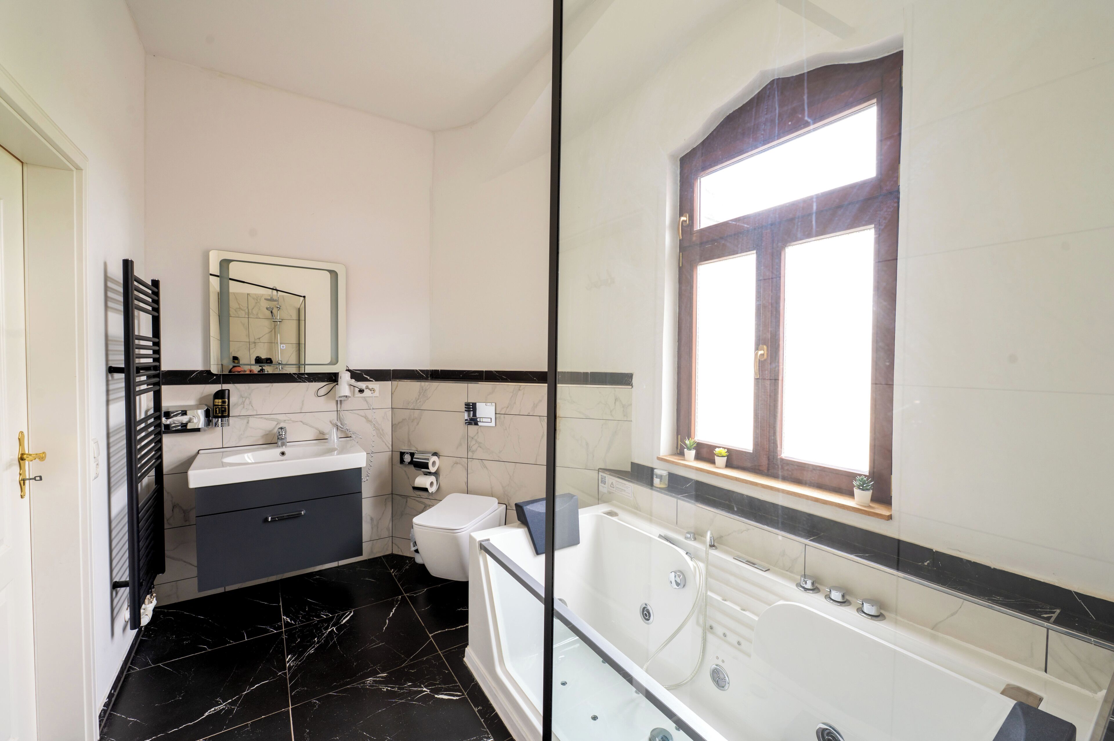 A bathroom with a bathtub, a toilet, a sink, a mirror, and a window.