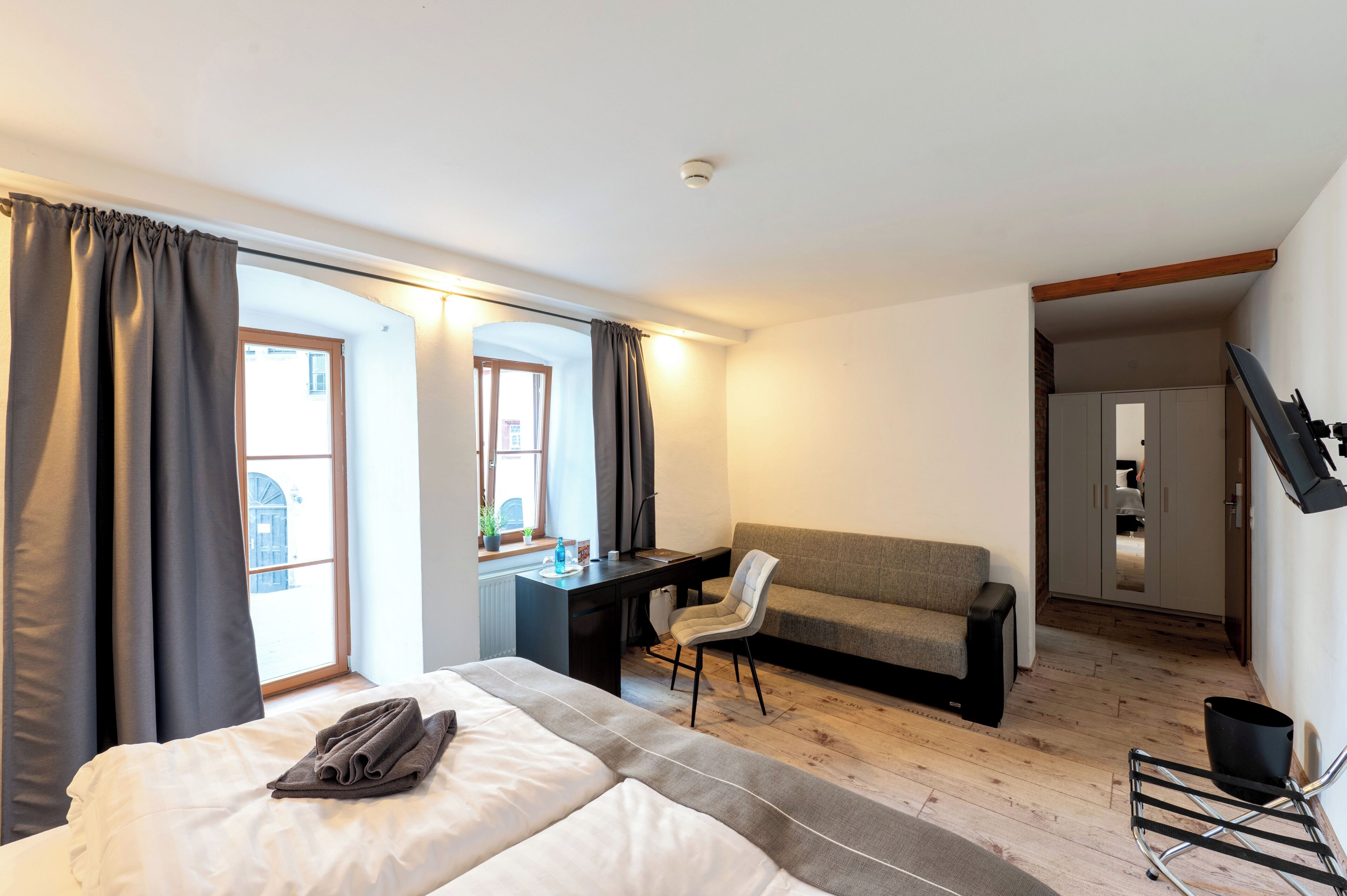 Ein Hotelzimmer mit Bett, Schreibtisch, Sessel, Sofa und Blick ins Freie.