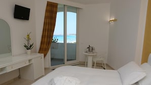 A hotel room with a bed, a desk, a chair, and a view of the sea. - Costa Brada (Gallipoli)