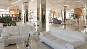 A spacious lobby with white leather sofas, a glass coffee table, and large windows allowing natural light. - Costa Brada (Gallipoli)