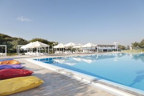 Une piscine avec des chaises longues et des parasols.