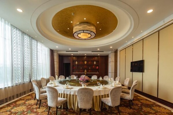 A conference room with a round table, chairs, and a chandelier.