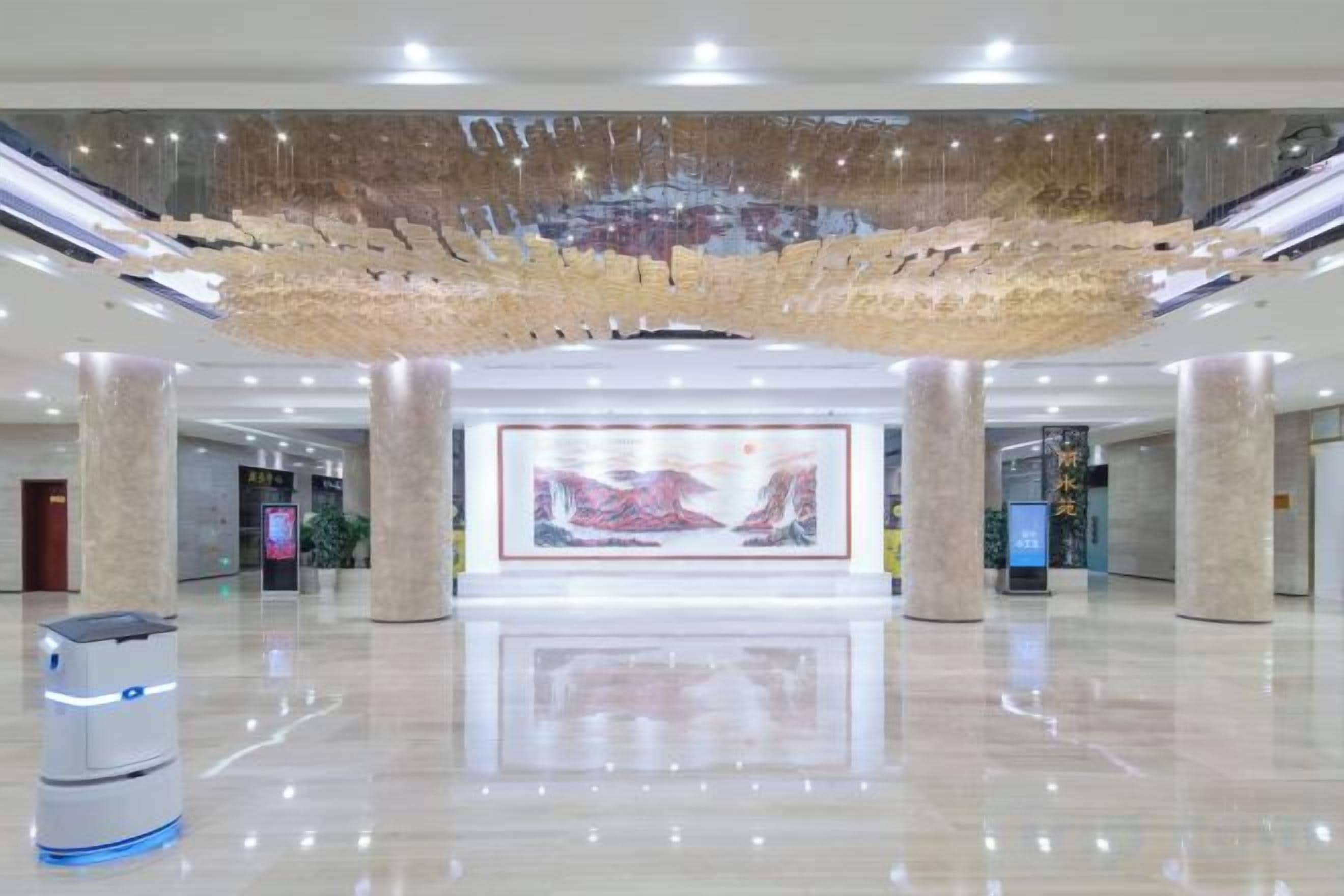 A spacious lobby with a large digital art display, a self-service kiosk, and a clean, reflective floor.