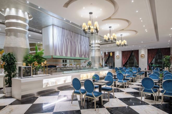 A hotel lobby with a check-in counter, seating area with chairs, and a decorative ceiling.