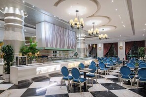 Un hall d’hôtel comprenant un comptoir d’enregistrement, un espace détente avec des fauteuils et un plafond décoratif.