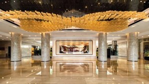 A spacious lobby with a high ceiling and a large, abstract golden installation.