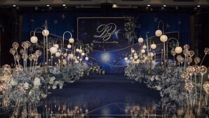 A stage with a backdrop featuring a monogram and the text "Welcome to our wedding."