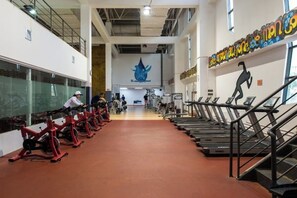Une salle de sport équipée de tapis de course, de vélos d’appartement et d’appareils de musculation.