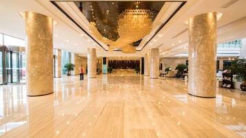 A spacious lobby with a polished floor, large columns, and a central chandelier.