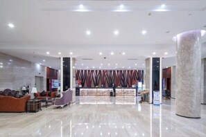 Ένας ευρύχωρος χώρος υποδοχής με γραφείο ρεσεψιόν, καθιστικό και έναν μεγάλο κολόνα.