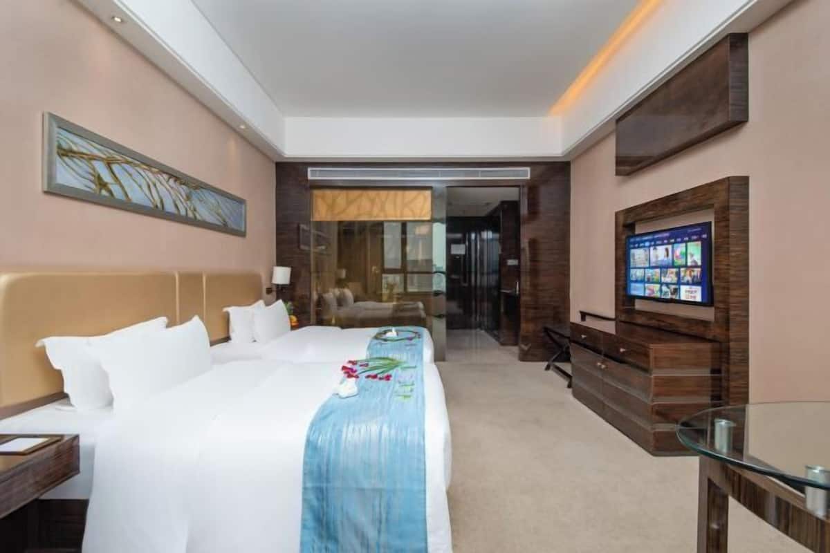Une chambre d’hôtel avec un grand lit, une télévision, un bureau et une table basse en verre.