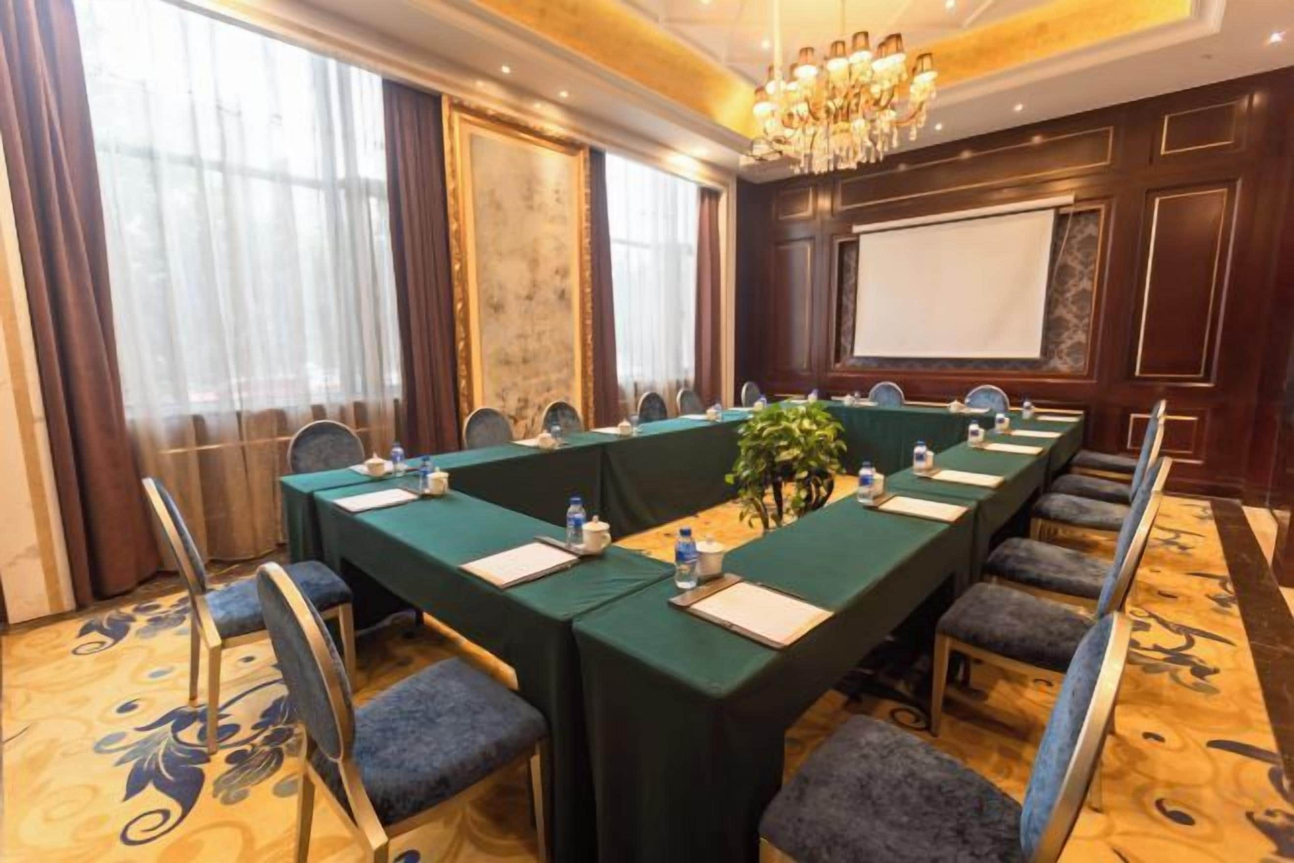 A conference room with a long table, chairs, and a projector screen.