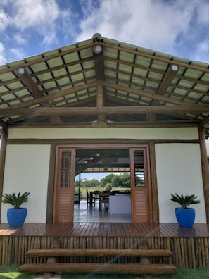 A covered outdoor area with a wooden deck, a pergola, and potted plants.