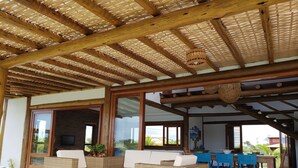 A covered outdoor seating area with wicker furniture and a wooden ceiling structure.
