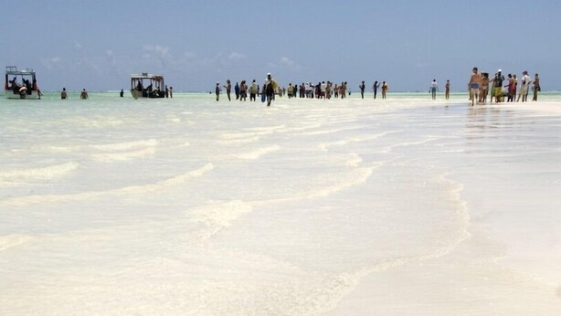 Uma praia com pessoas e barcos.