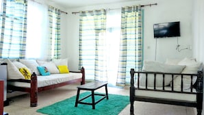 Quarto com cama, sofá, televisão e cortinas.