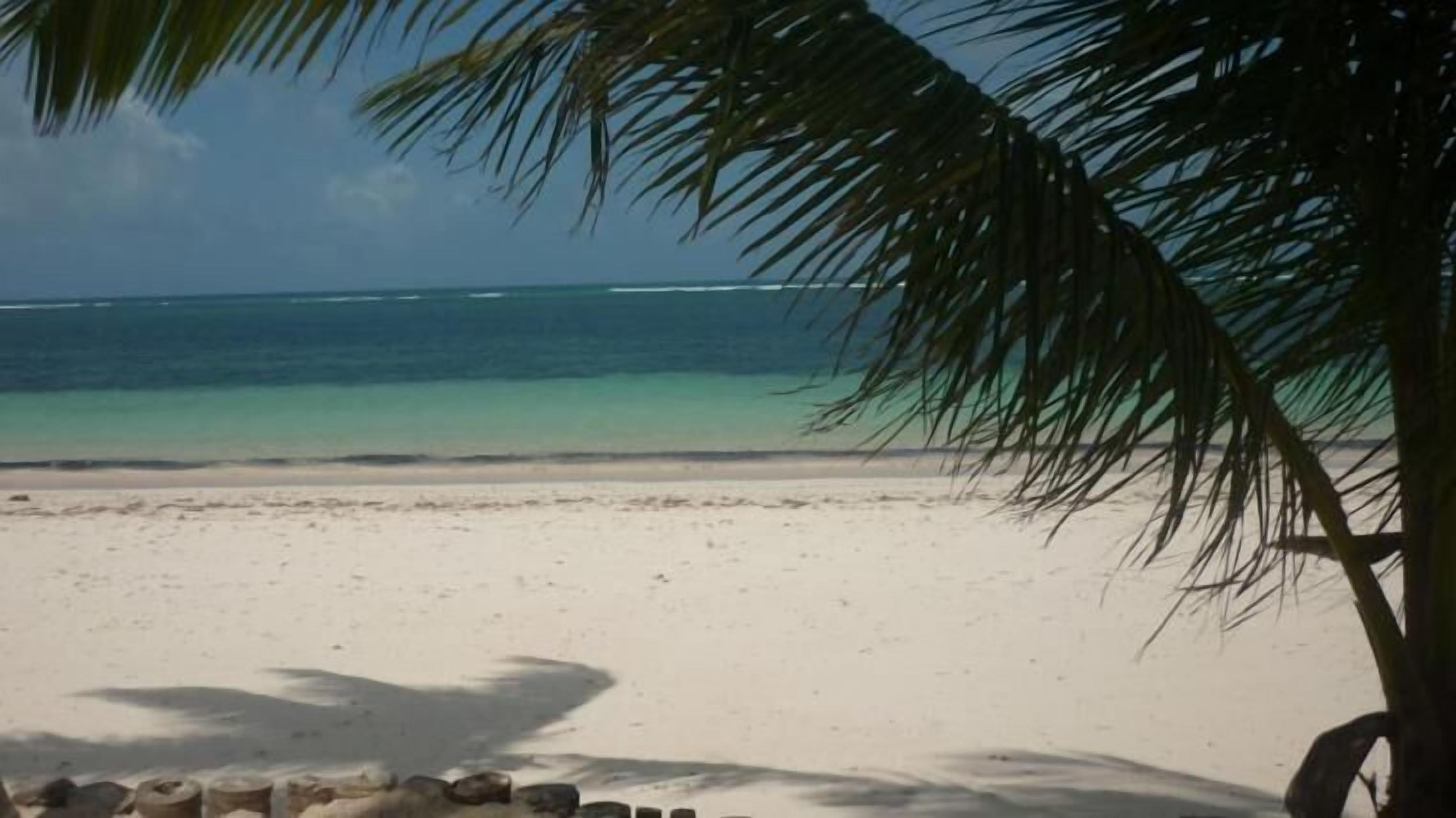 A beach with clear turquoise water and a sandy shore.