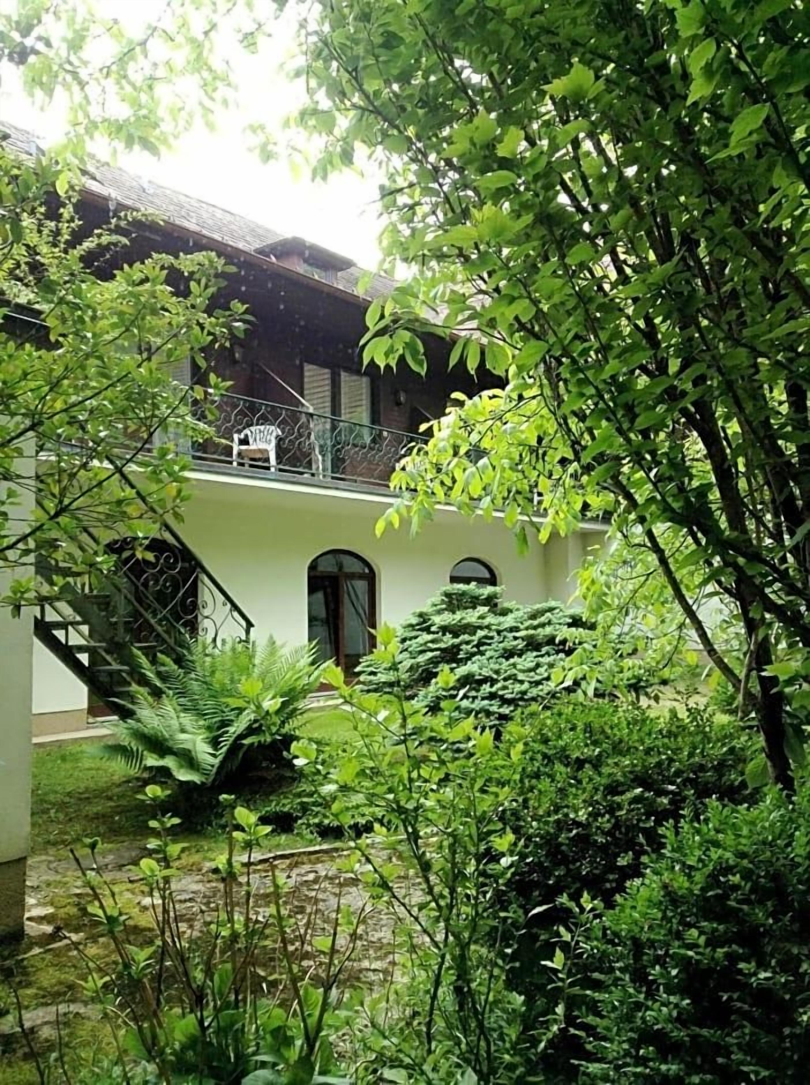 Ein Gebäude mit einer Treppe, die zu einem Balkon führt, umgeben von üppigem Grün.